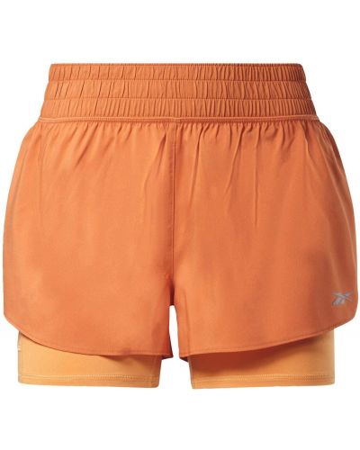 Jednofarebné teplákové nohavice skinny fit z polyesteru Reebok Sport - oranžová