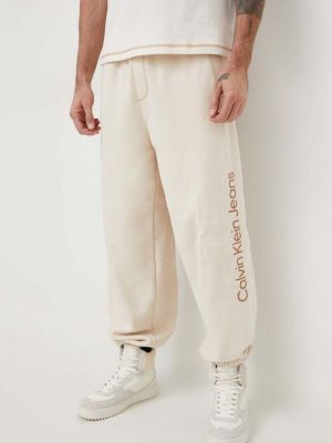 Bavlněné sportovní kalhoty s aplikacemi Calvin Klein Jeans béžové