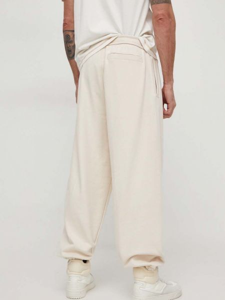 Bavlněné sportovní kalhoty s aplikacemi Calvin Klein Jeans béžové