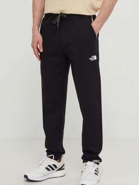 Spodnie sportowe bawełniane z nadrukiem The North Face czarne